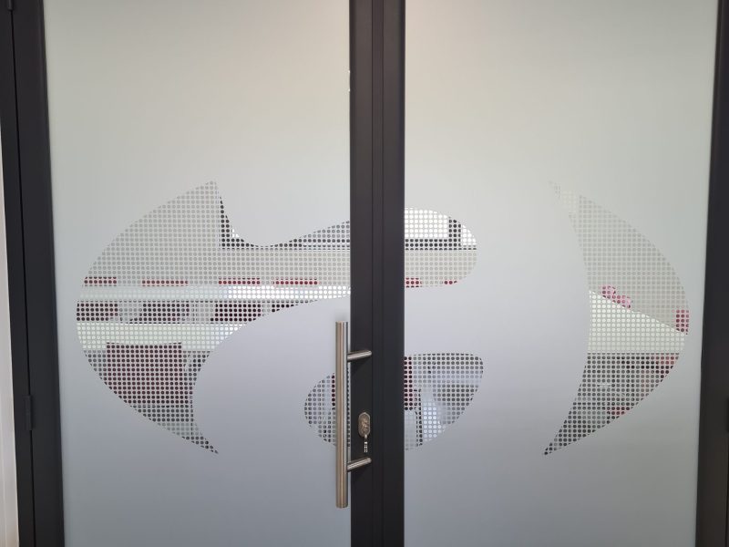 Porte vitrée couverte d'un film dépoli avec un logo réalisé en film micro-perforé