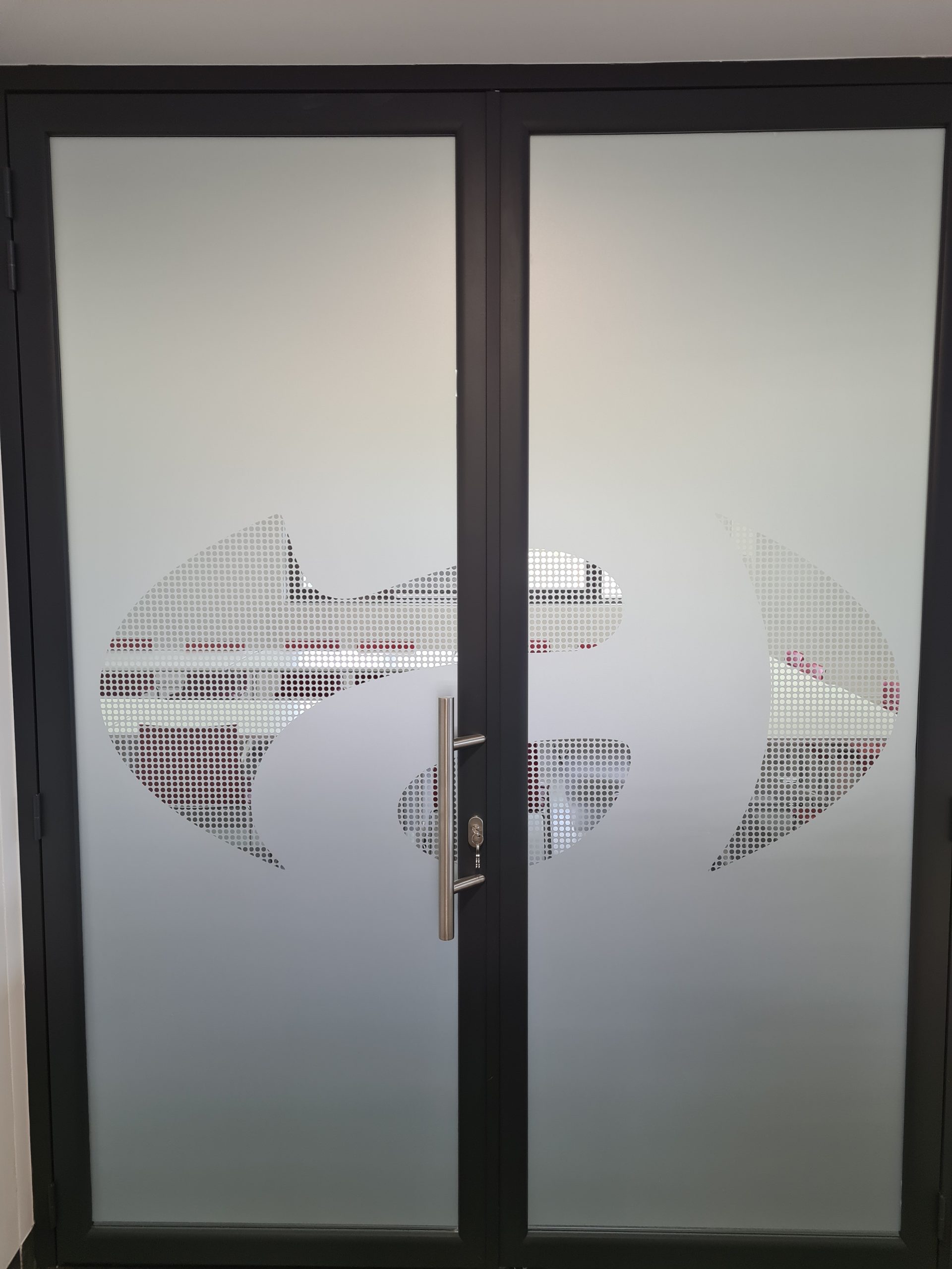 Porte vitrée couverte d'un film dépoli avec un logo réalisé en film micro-perforé