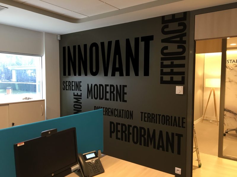 Mur de bureau couvert de mots en grandes lettres adhésives noires sur fond gris