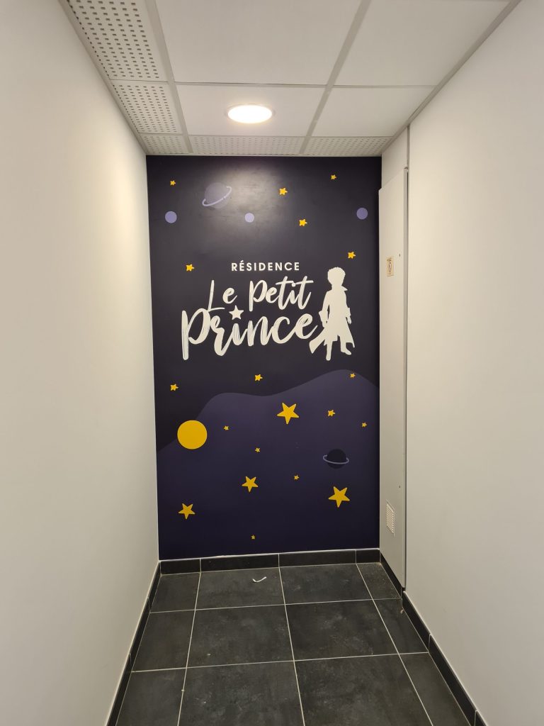Mur de hall couvert d'un décor imprimé étoilé au nom de la Résidence Le Petit Prince