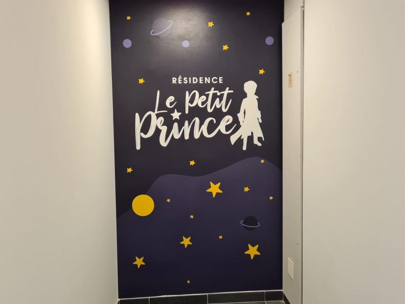 Mur de hall couvert d'un décor imprimé étoilé au nom de la Résidence Le Petit Prince