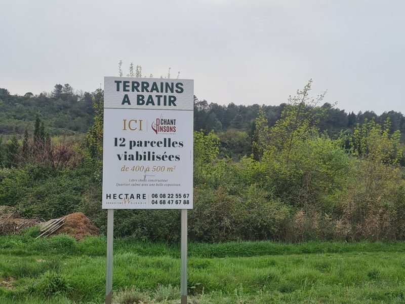 Panneau Terrains à bâtir monté sur deux poteaux au bord d'un terrain