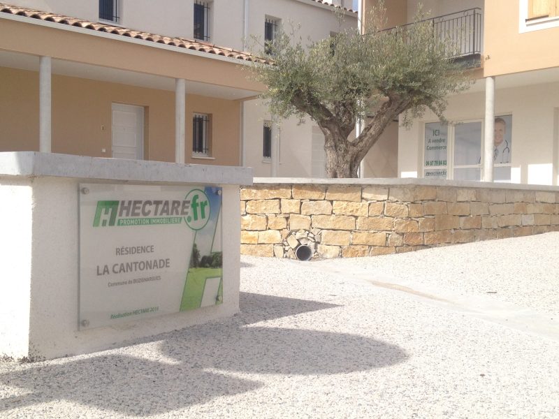 Plaque en plexiglas imprimée fixée sur entretoises à l'entrée d'une résidence