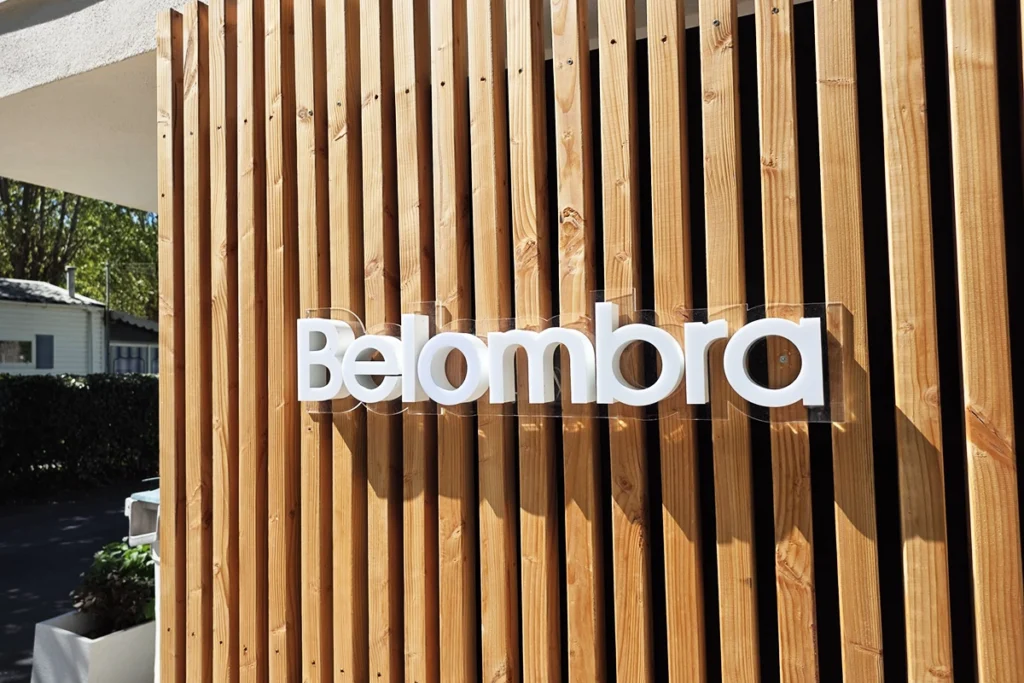 Enseigne en lettres découpées blanches posée sur un bardage à lames de bois
