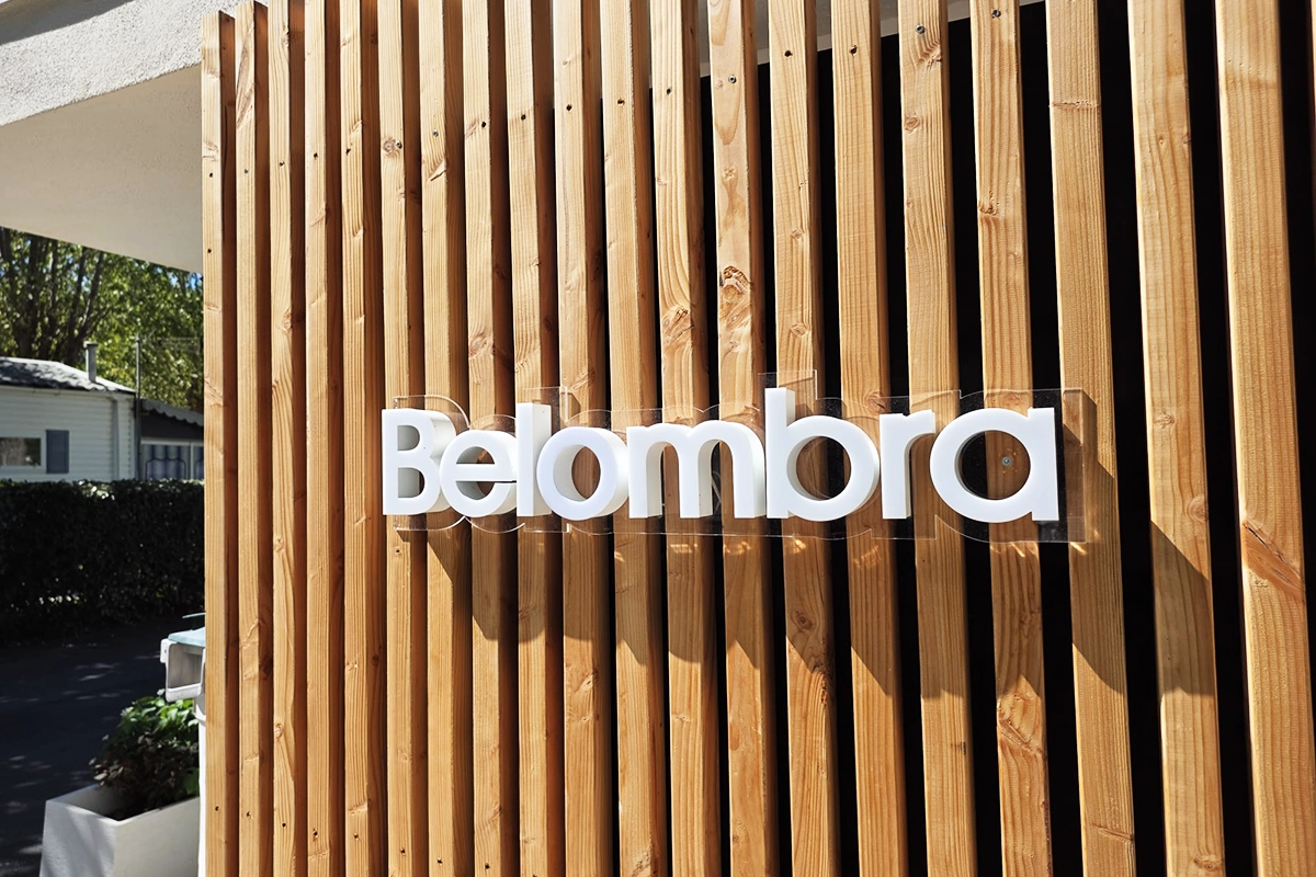 Enseigne en lettres découpées blanches posée sur un bardage à lames de bois