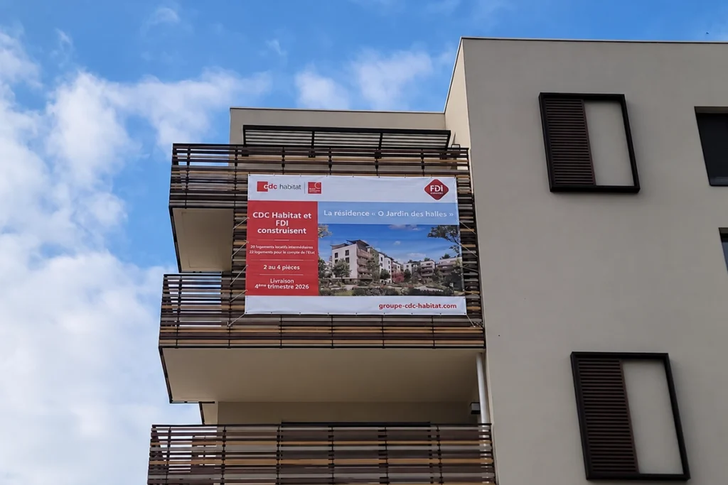 Impression publicitaire sur drapeaux : trois drapeaux blancs au nom d’une cave, hissés sur de grands mâts en bordure de parking